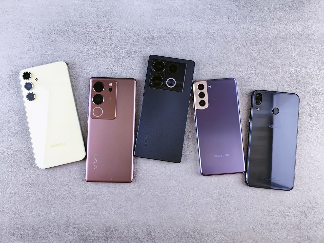 Services Flat lay of five modern smartphones on a gray surface, showcasing various designs.