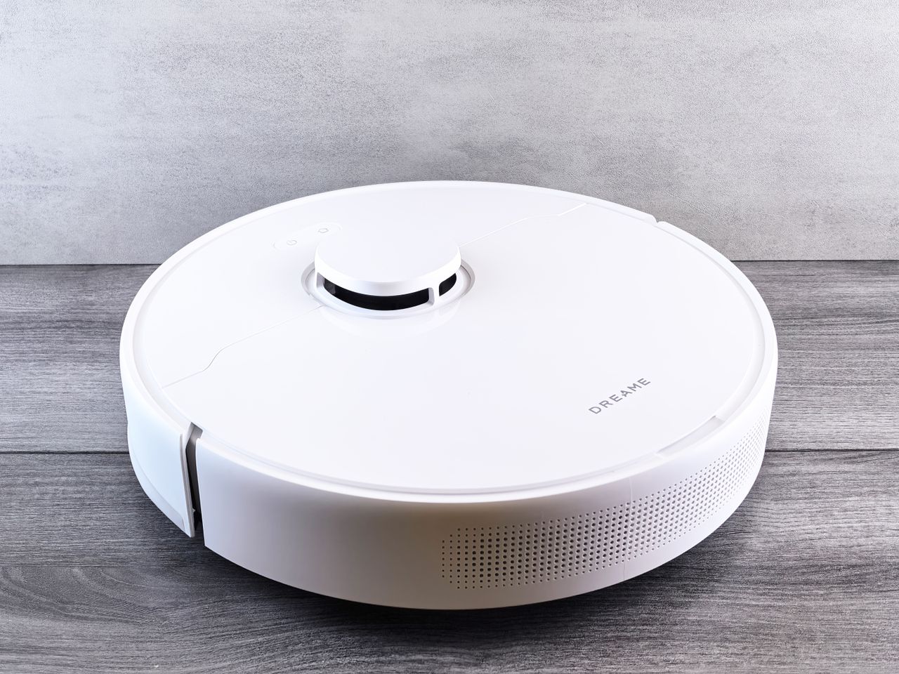 Services Sleek white robot vacuum cleaner on a wooden floor, perfect for smart home setups.
