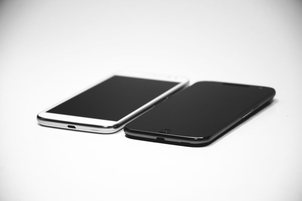 Services Two smartphones, one black and one white, placed on a white surface, showcasing modern design.
